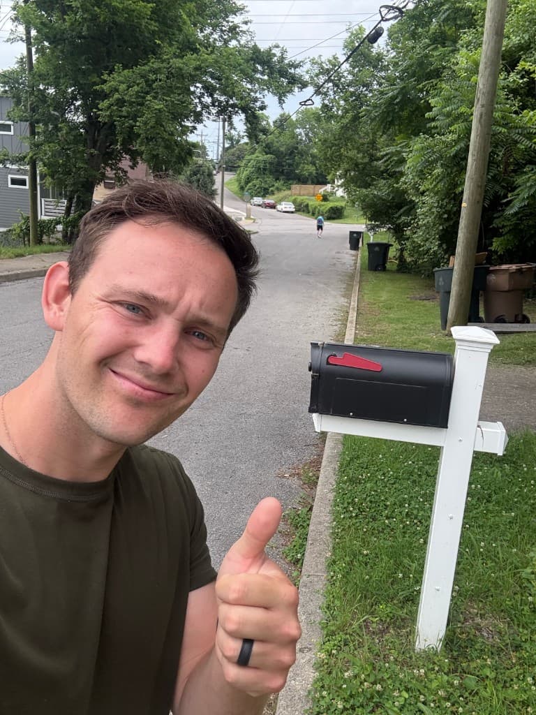 Mailbox Bros team member giving a thumbs up beside a new black and white mailbox install